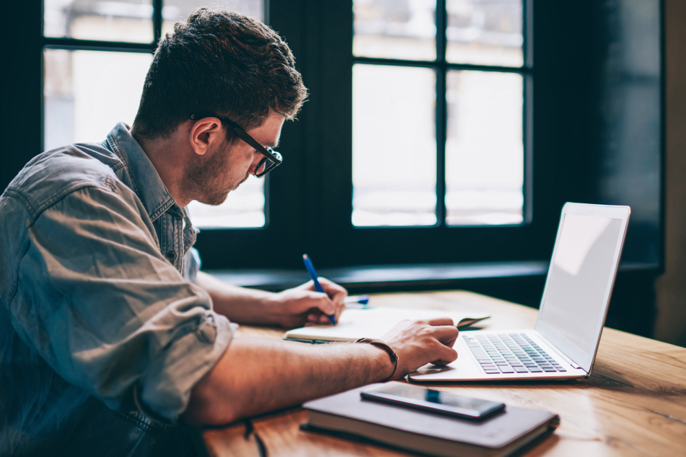 a content writer working on a laptop and making notes
