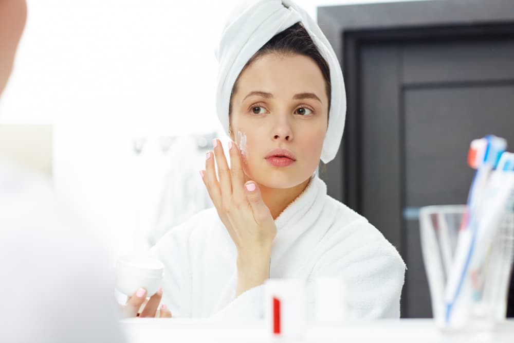 A woman applying a cream on her face for her skin treatment overnight